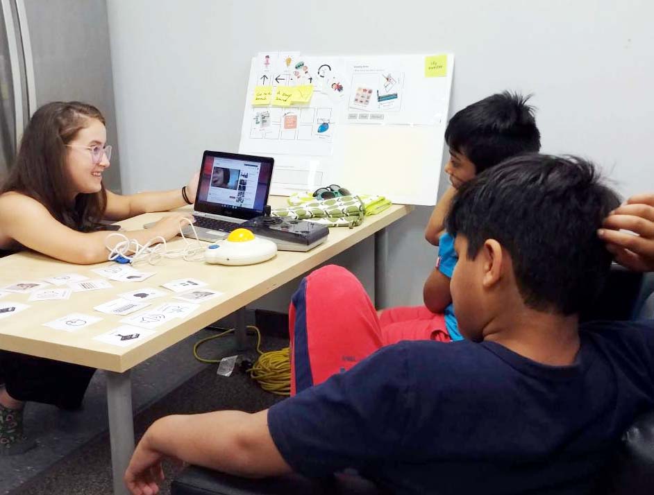 A facilitator showing a video on a laptop to two kids. 